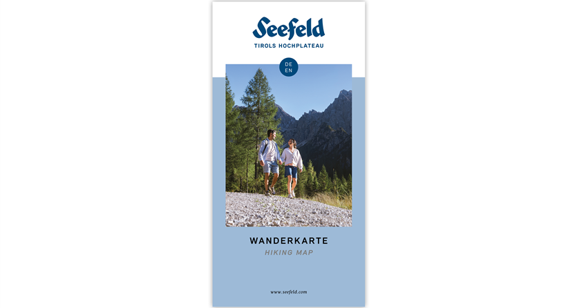 Eine Wander- und Bikerkarte für die Region Seefeld. Im Hintergrund sind grüne Hügel und Berge zu sehen.