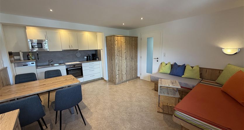 Een moderne, lichte woning met een gezellige zithoek en een eetgedeelte. De keuken is goed uitgerust en de inrichting is vriendelijk en uitnodigend.