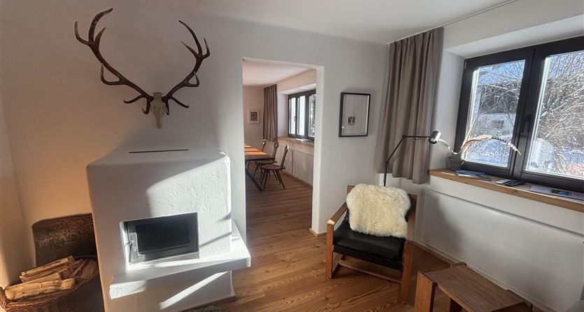 Uno spazio abitativo accogliente con un camino moderno e pavimento in legno. Sulla parete è appeso un trofeo e la finestra offre luce e vista.