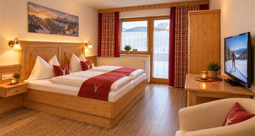 A cozy room with a double bed and wooden furniture. Through the window, there is a view of the mountains.