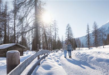 Hofladenrunde im Winter_zwei Frauen laufen auf Oberen Wiesenweg_Aufnahme mit Hütte.jpg