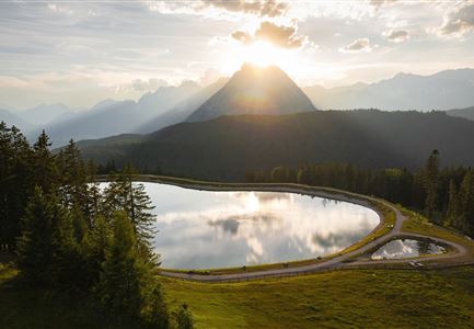 Drohnenaufnahme Gschwandtkopf - Speichersee mit Bäumen und Hohe Munde bei Sonnenuntergang.jpg