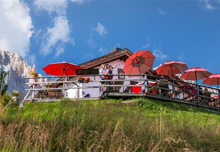 Familien-Weitwanderung im Gaistal - Familie steht auf Terasse bei der Wettersteinhütte - Vater zeigt auf etwas.jpg