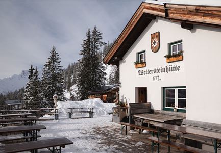 Wettersteinhütte im Winter - Aufnahme von der Seite mit Sitzbänken.jpg