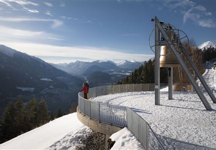 Winterwandern Paar Friedensglocke Drohnen Nahaufnahme Paar steht am Geländer Blick ins Inntal (1).jpg