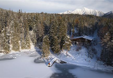 Winterwandern Paar Möserer See Drohnenaufnahme Paar steht am Steg mit Möserer Seestube und Reither Spitze im Hintergrund (1).jpg